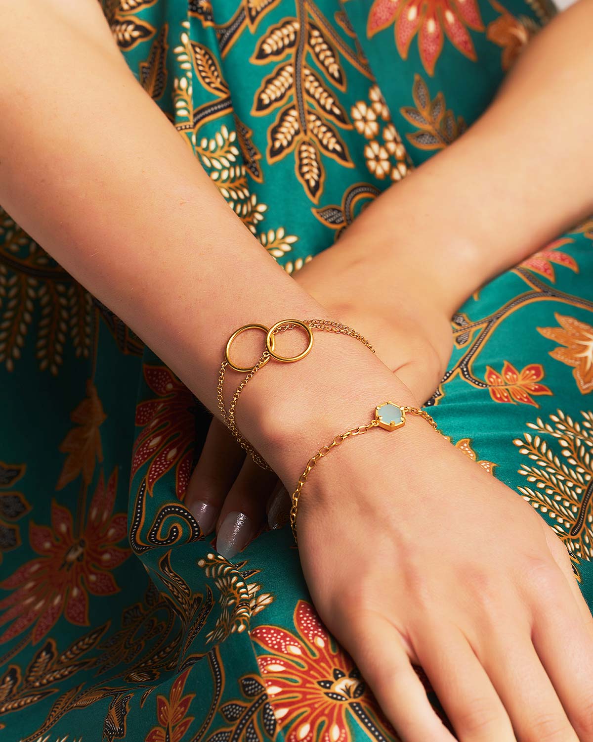 Close-up of a gold adjustable bracelet with a faceted aqua chalcedony gemstone