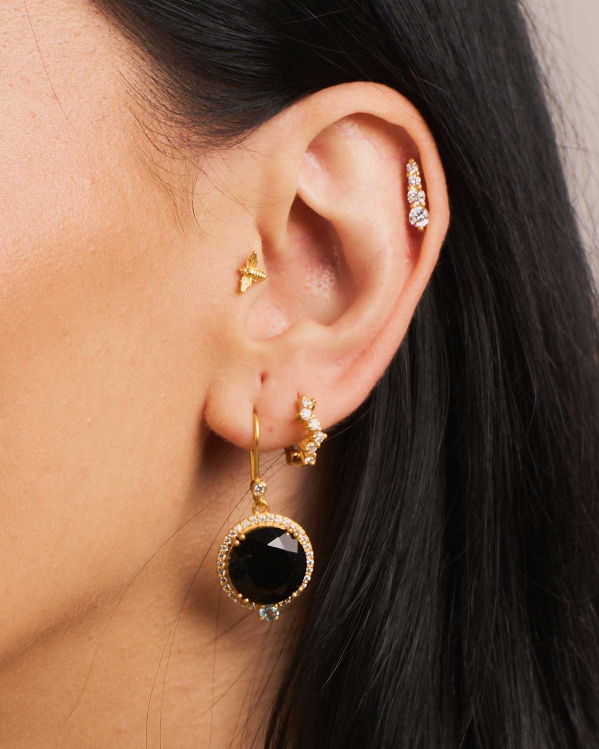 Close-up of mini gold bee stud earrings with fine detailing