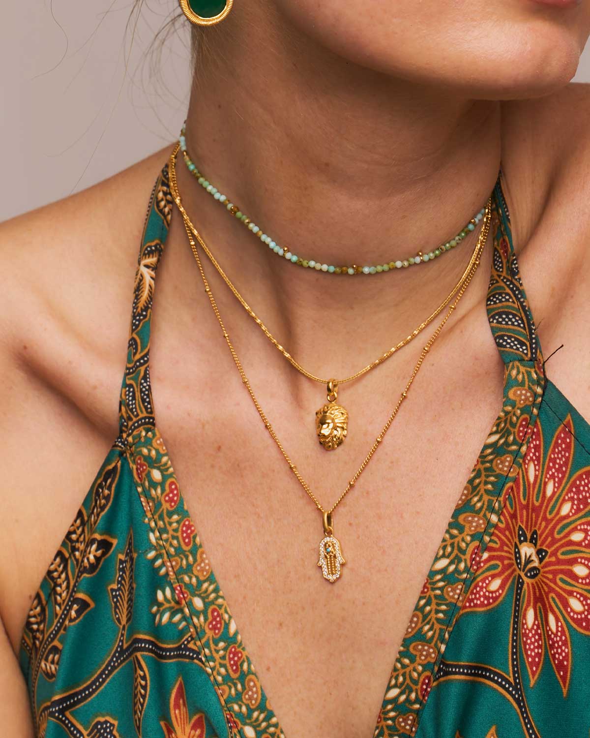 Close-up of a gold necklace pendant with turquoise gemstone and tiny lab diamonds