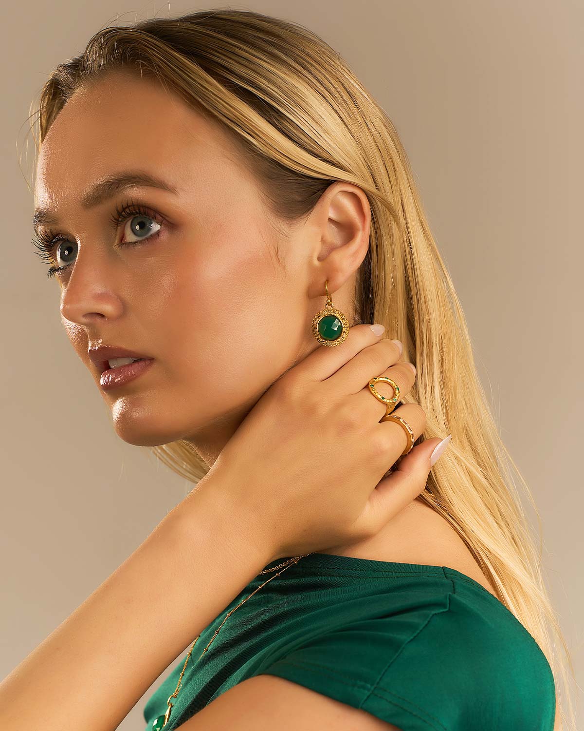 Model wearing circular gold earrings with bold green onyx gemstones