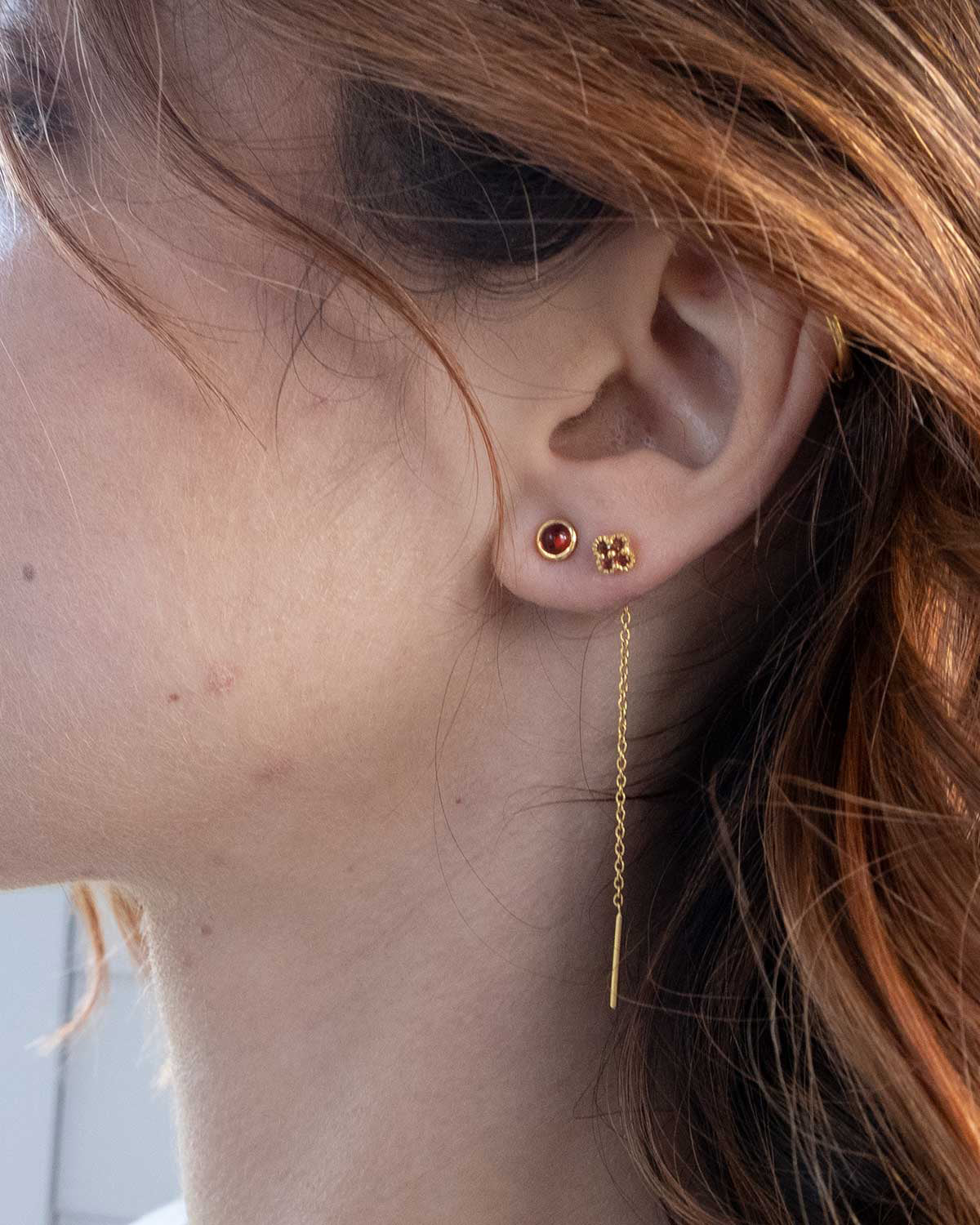 Side view of small garnet stud earrings in a secure setting