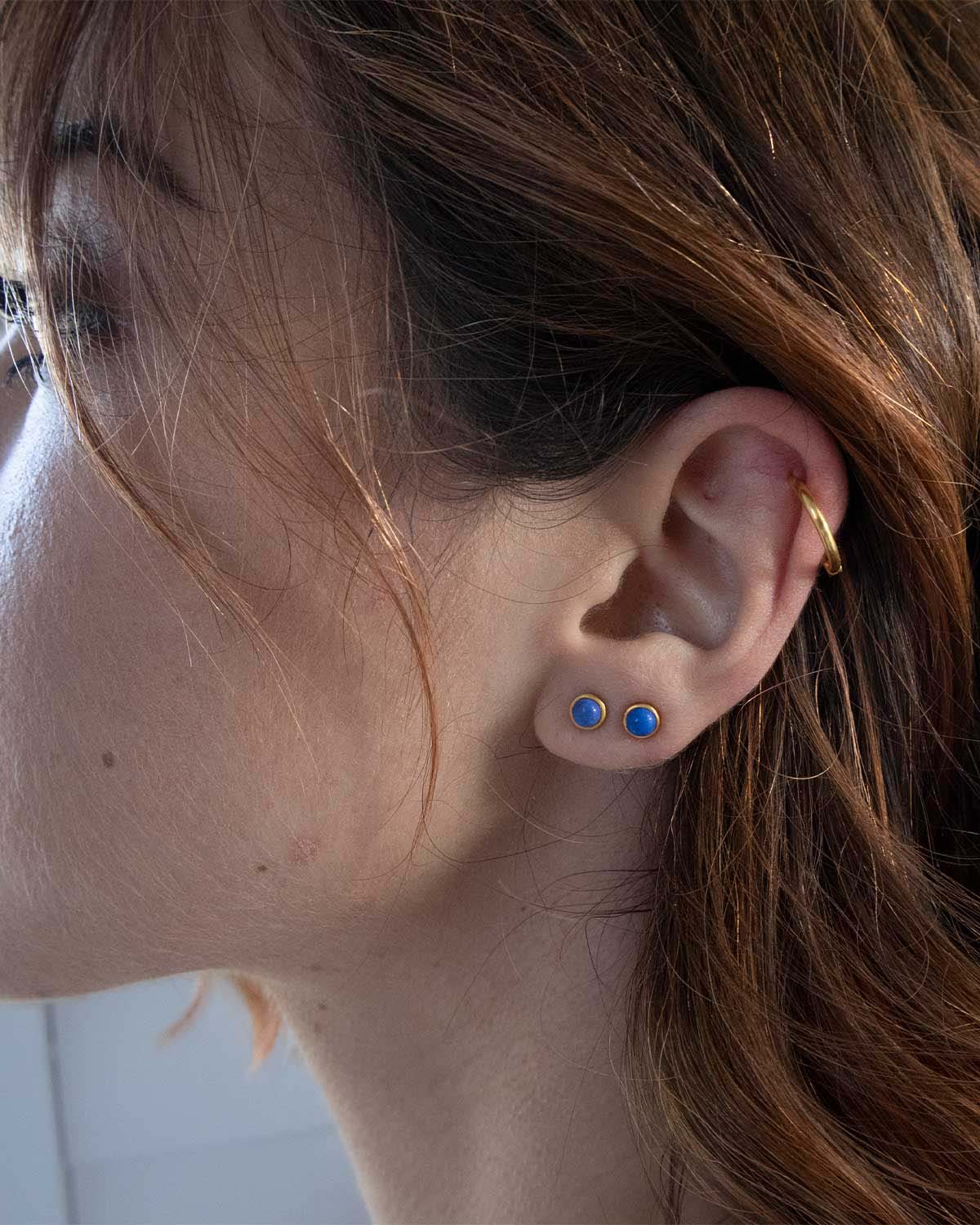 Lapis lazuli stud earrings styled in a stacked ear look