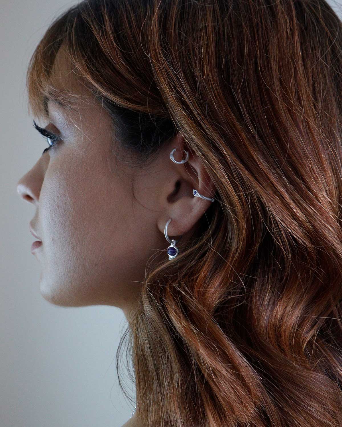 Side angle of silver mini hoops with removable lapis lazuli charm