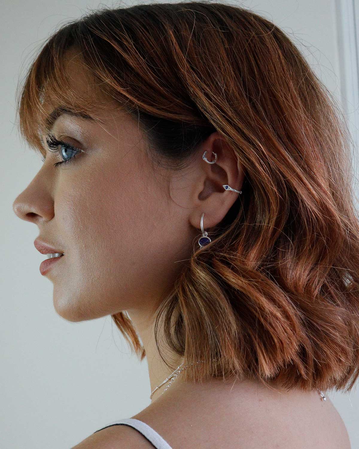 Model wearing silver mini hoops with rainbow moonstone charm