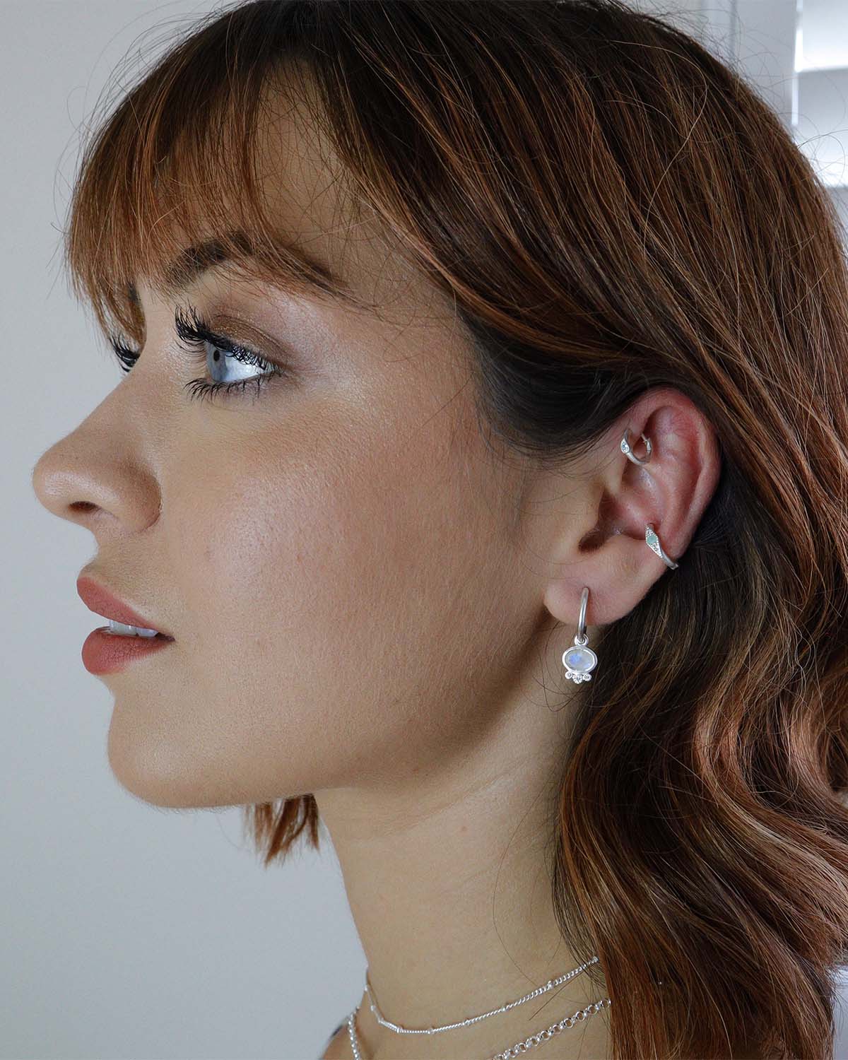 Side angle of silver mini hoops with rainbow moonstone and crystal accents