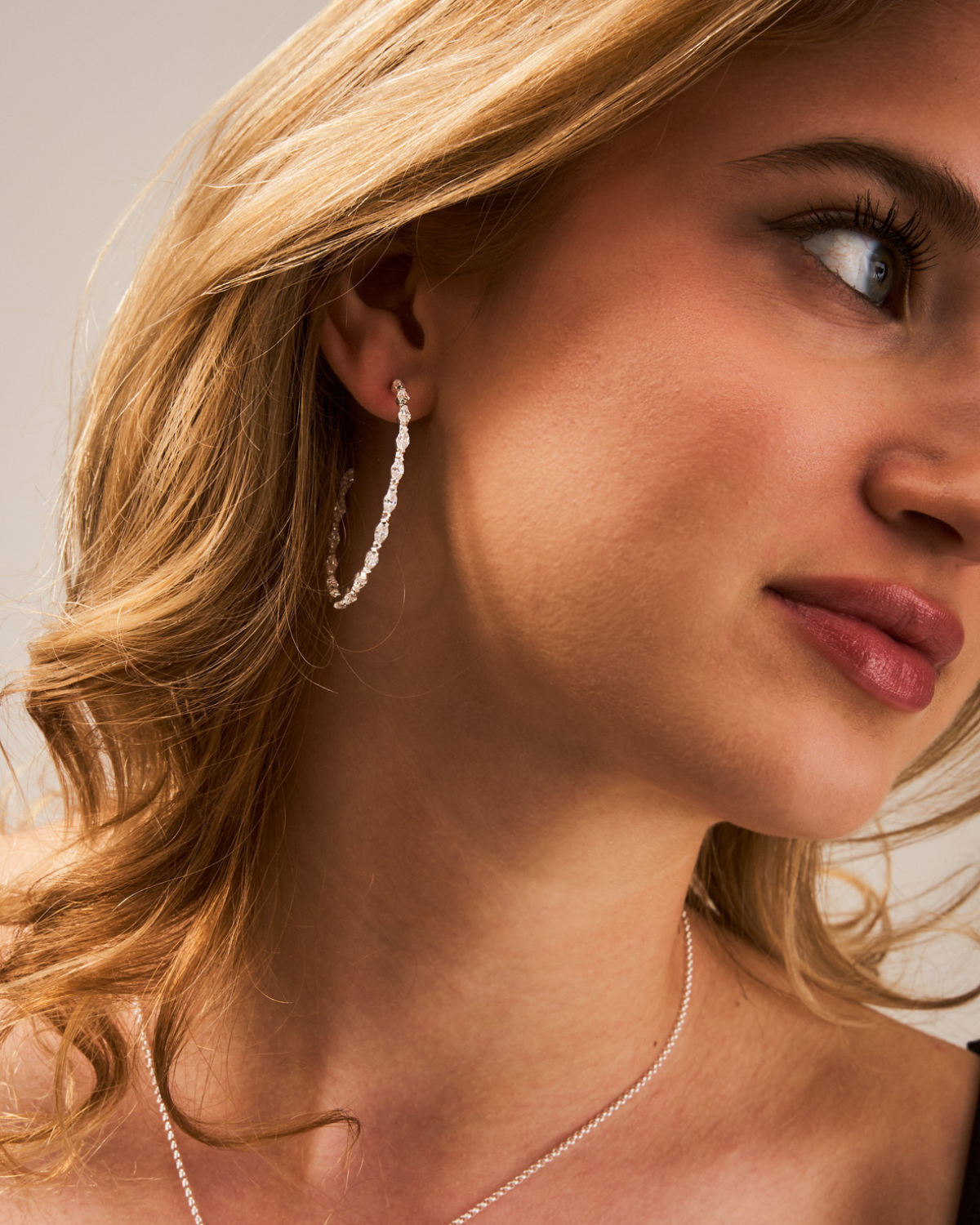 Side angle view of sparkling silver hoop earrings with zirconia gemstones