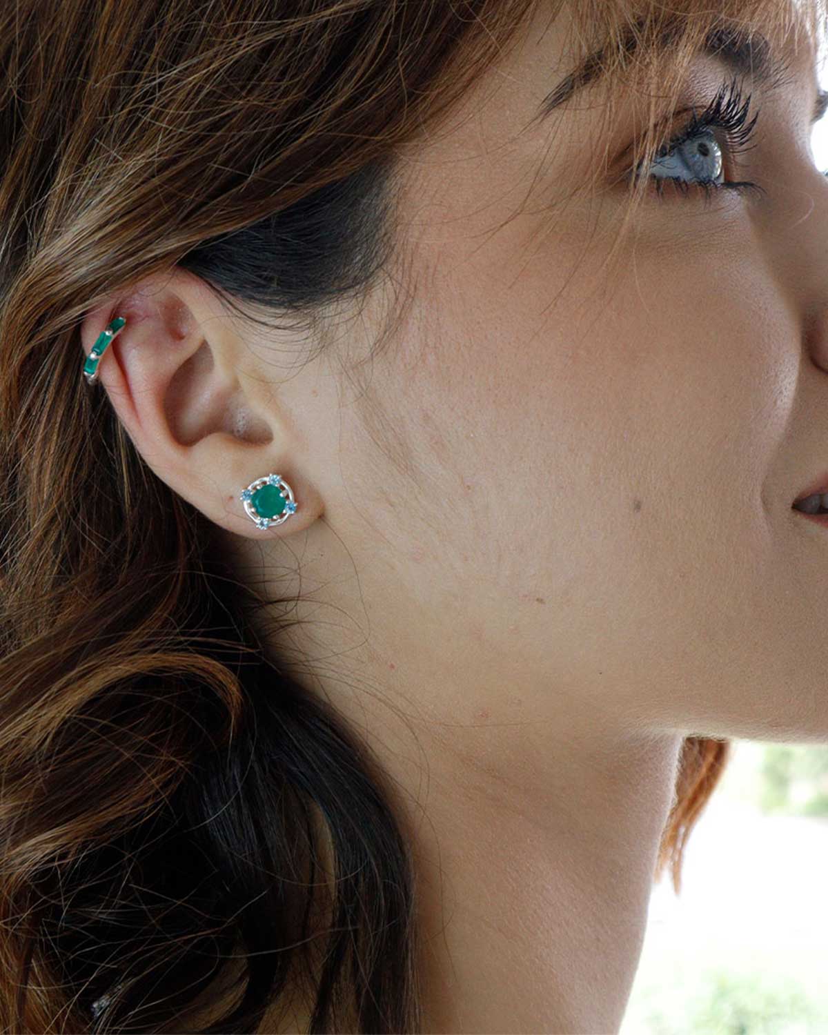 Model wearing silver stud earrings with green onyx and blue topaz