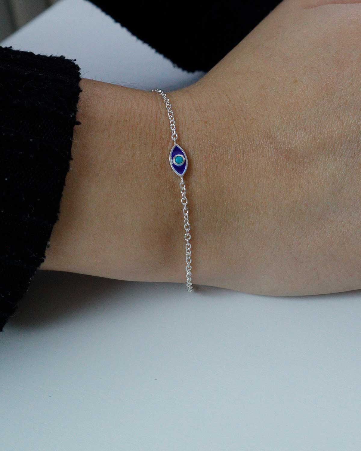 Silver evil eye bracelet styled with other bracelets in a stack