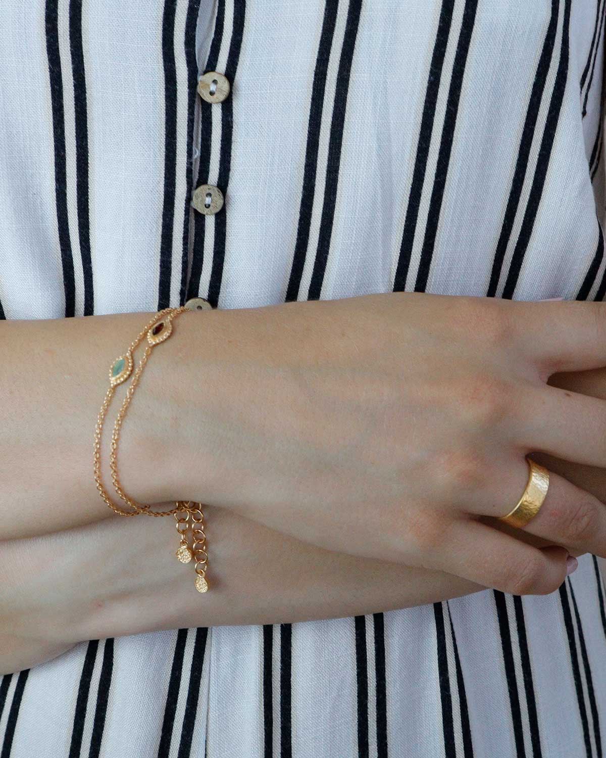 Model wearing gold bracelet with eye motif and mixed gemstones