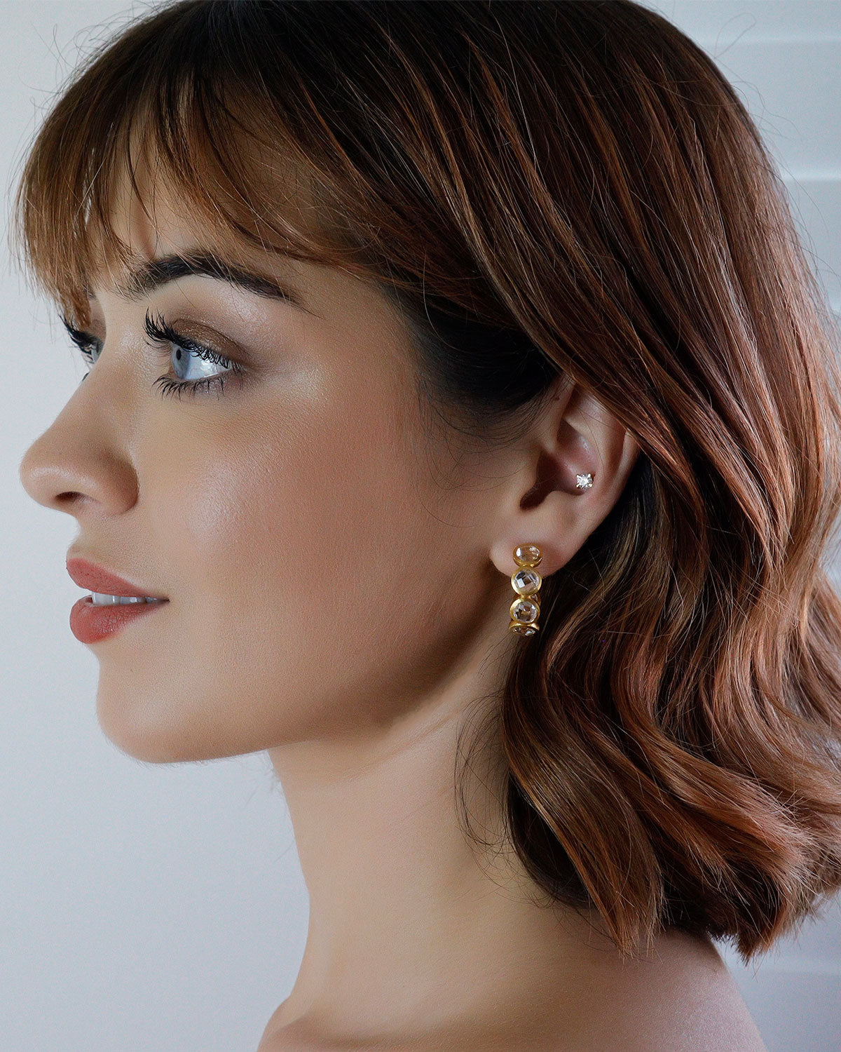 Gold diamond stud earrings styled for stacking with other earrings