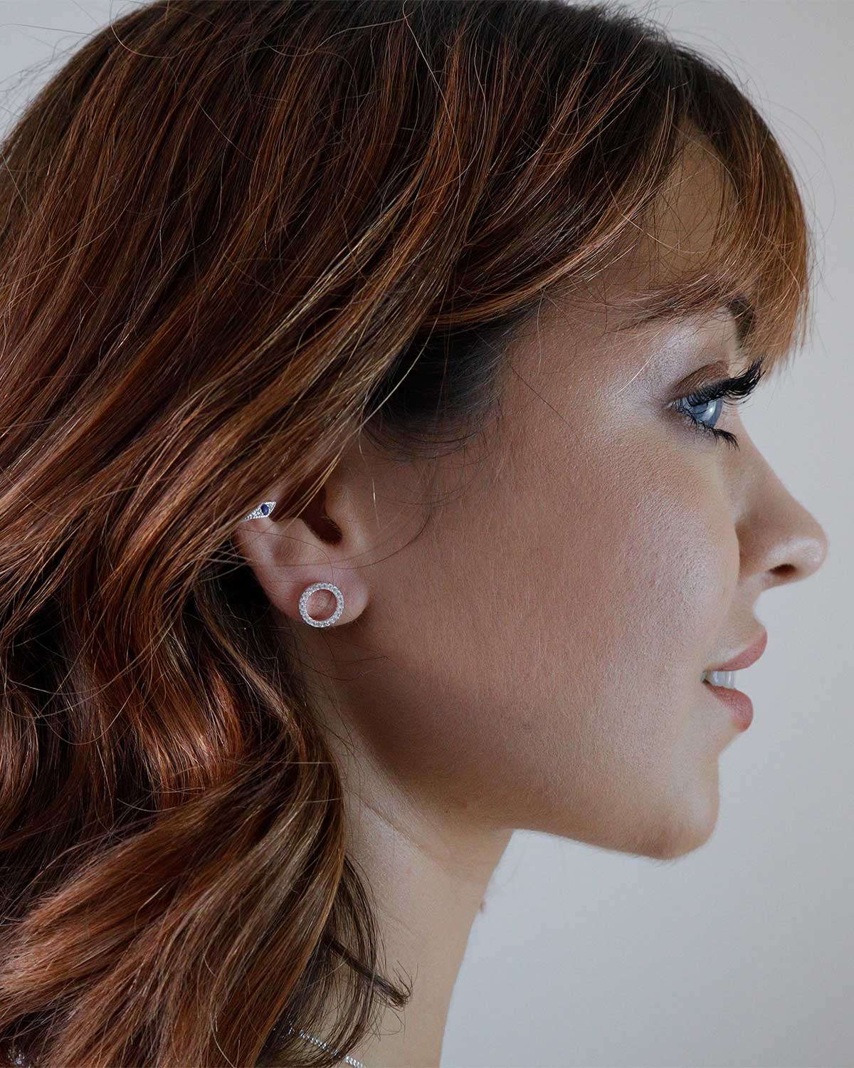 Model wearing circular silver stud earrings with crystal detailing