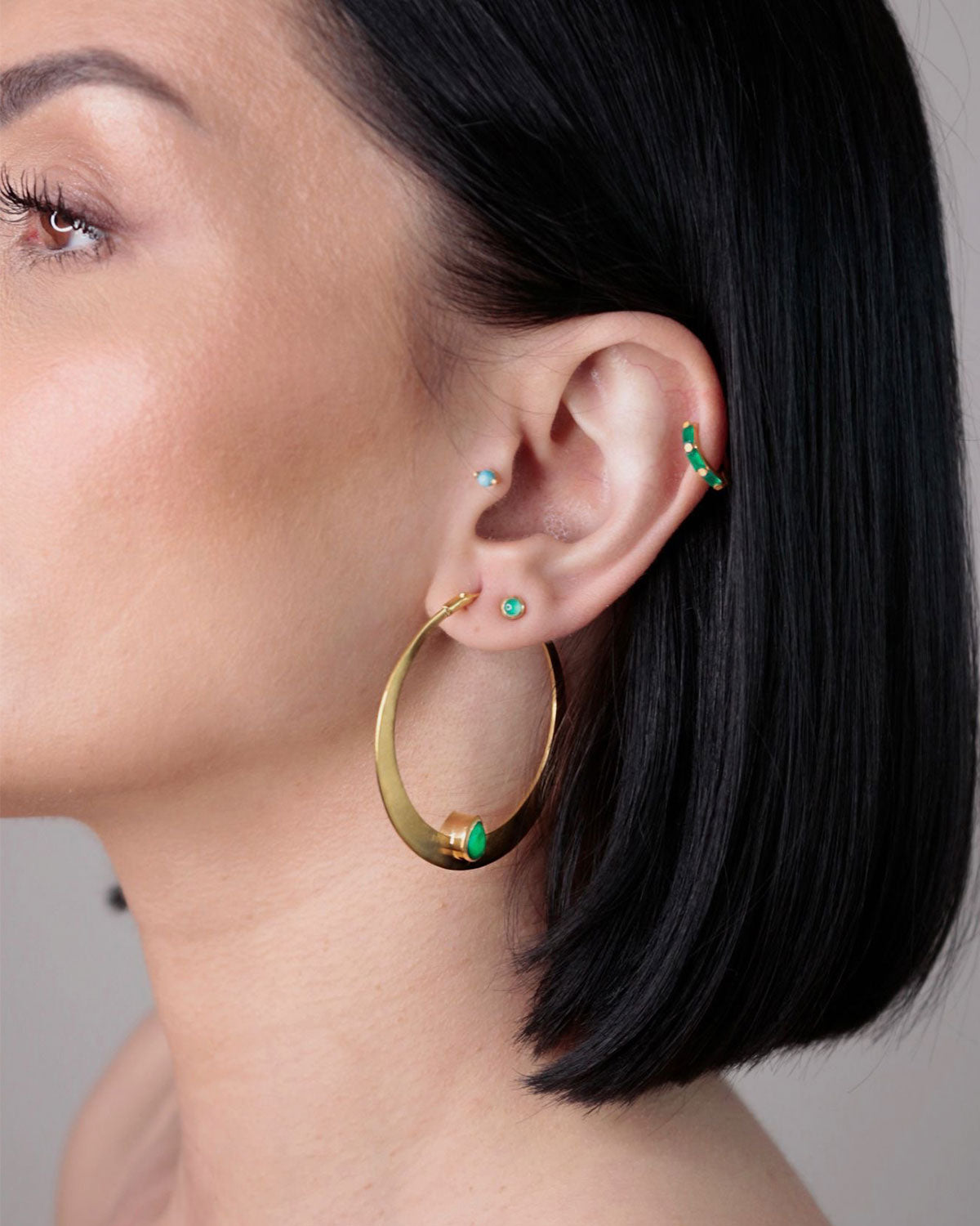 Close-up of large gold hoop earrings with green onyx gemstones