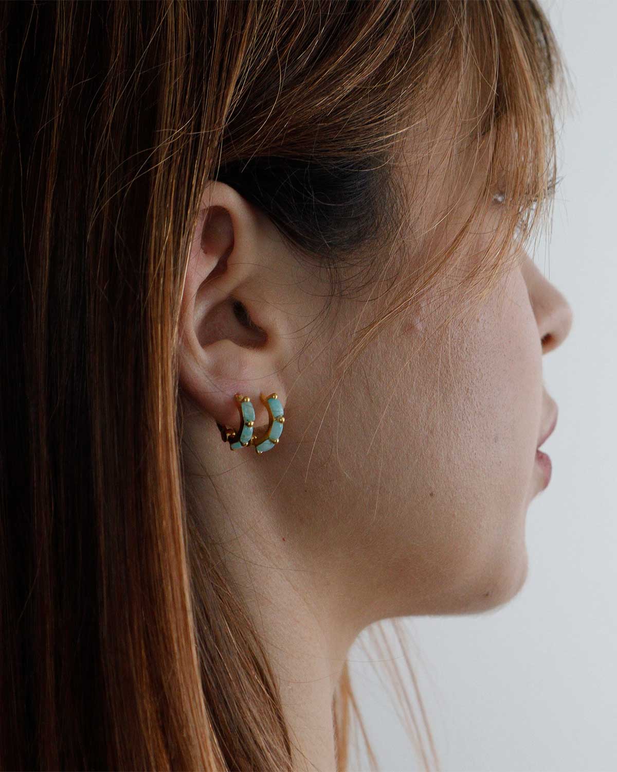 Detailed view of baguette-cut amazonite gemstones on gold mini hoop earrings