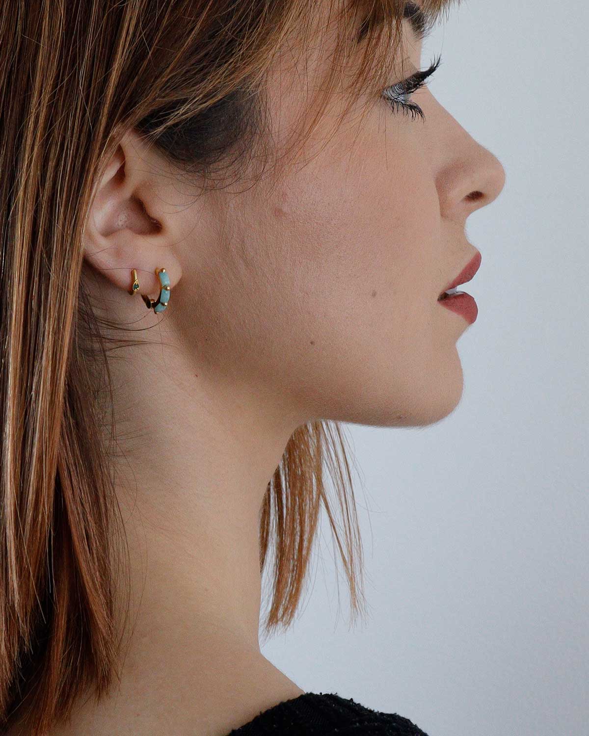 Gold mini hoop earrings with amazonite gemstones styled with other earrings