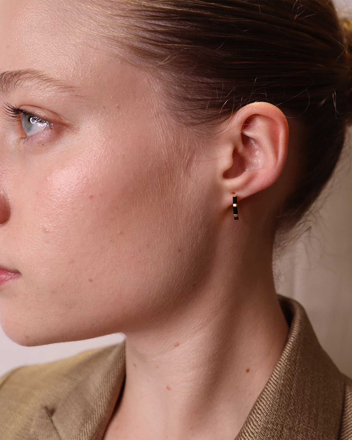 Close-up showing baguette-cut black spinel gemstones on gold mini hoops