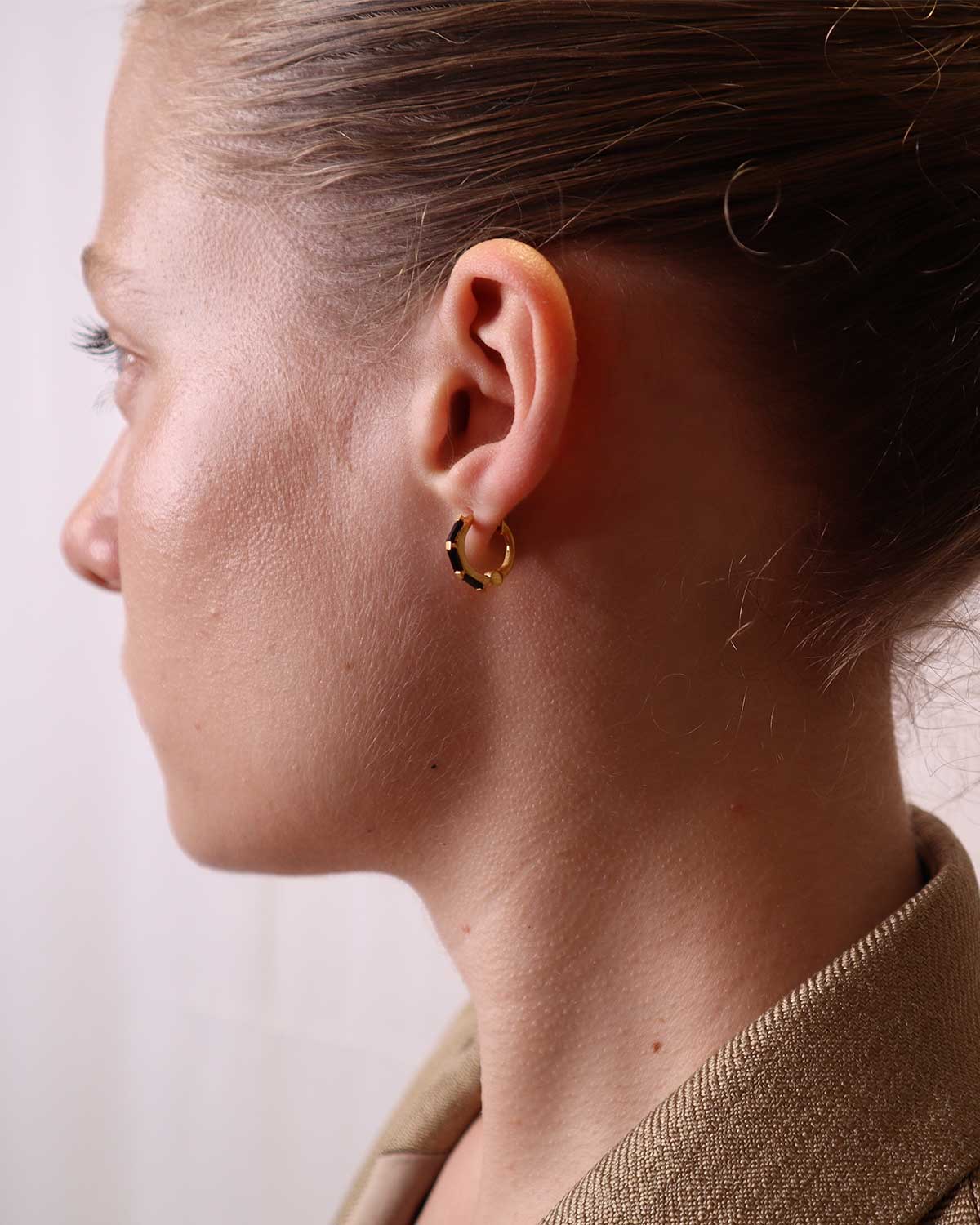 Gold mini hoops with black spinel gemstones styled with other earrings