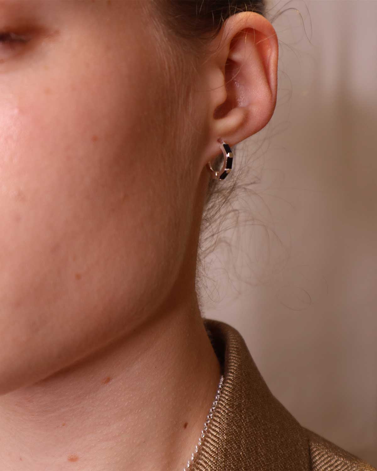 Model wearing silver mini hoop earrings with black spinel gemstones