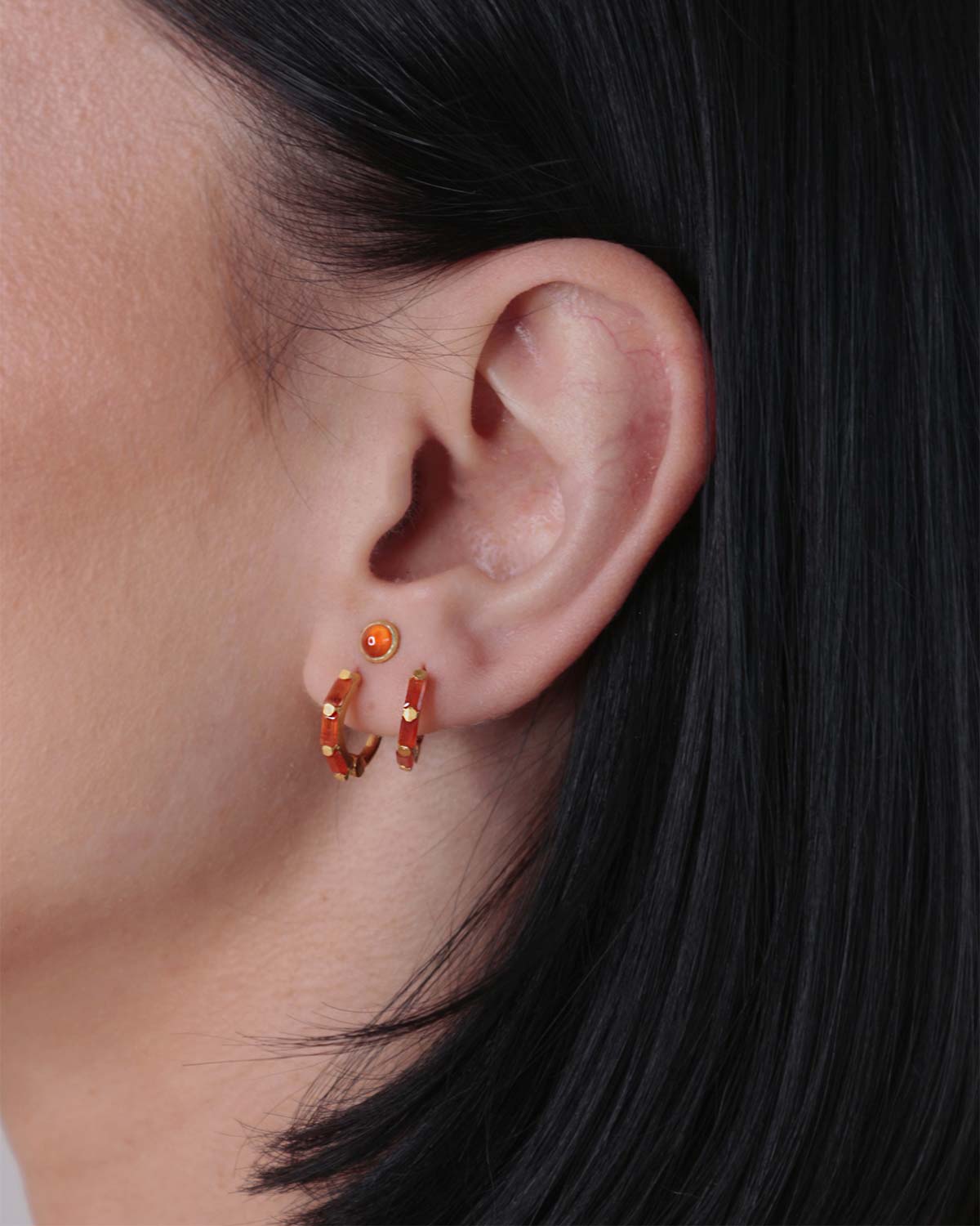 Close-up of gold mini hoop earrings with baguette-cut carnelian gemstones