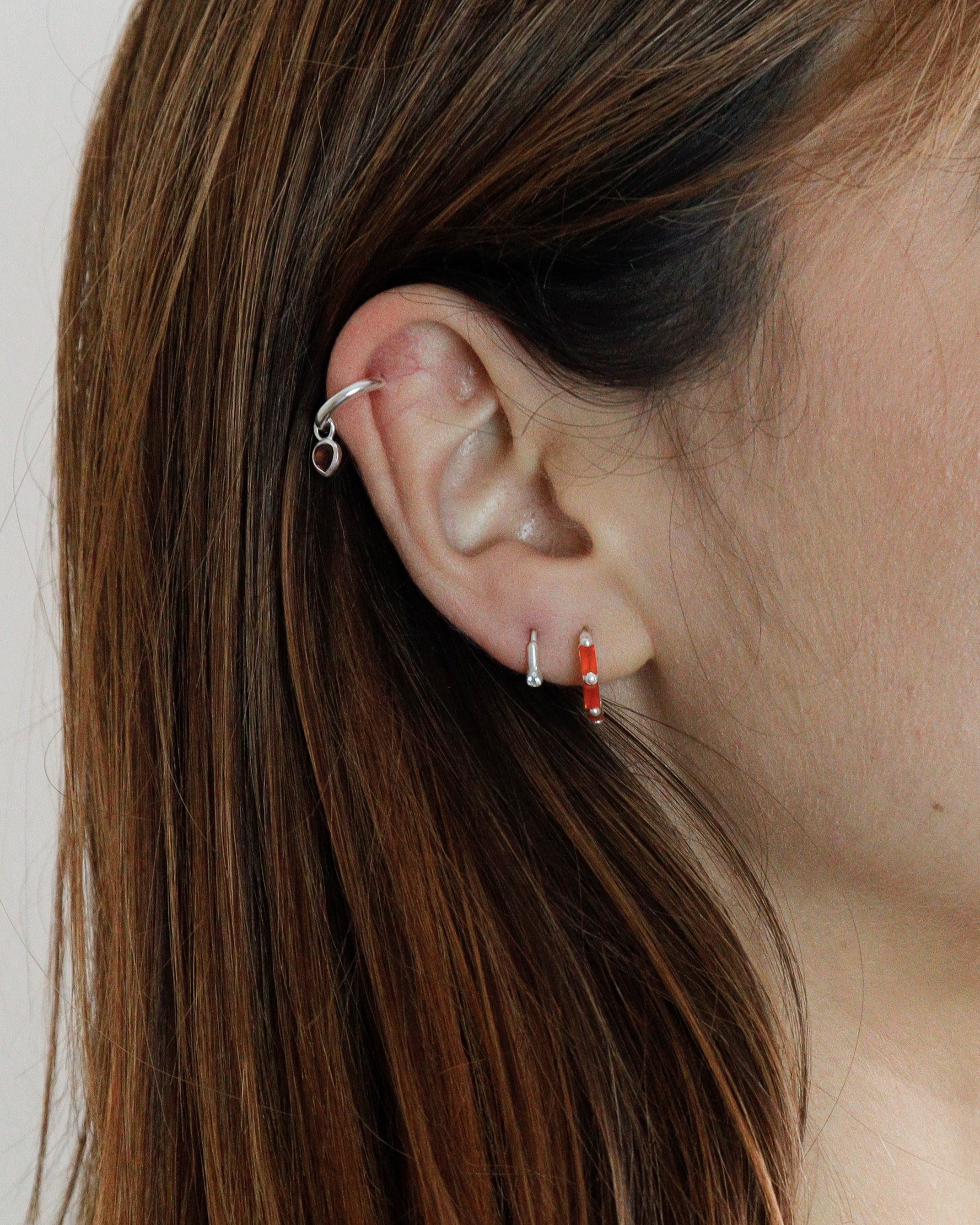 Model wearing gold mini hoop earrings with carnelian gemstones