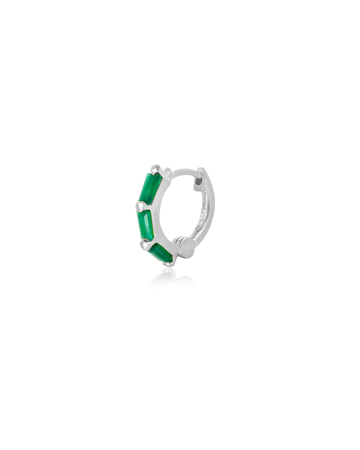 Silver mini hoop earrings with emerald green gemstones styled in a stacked look