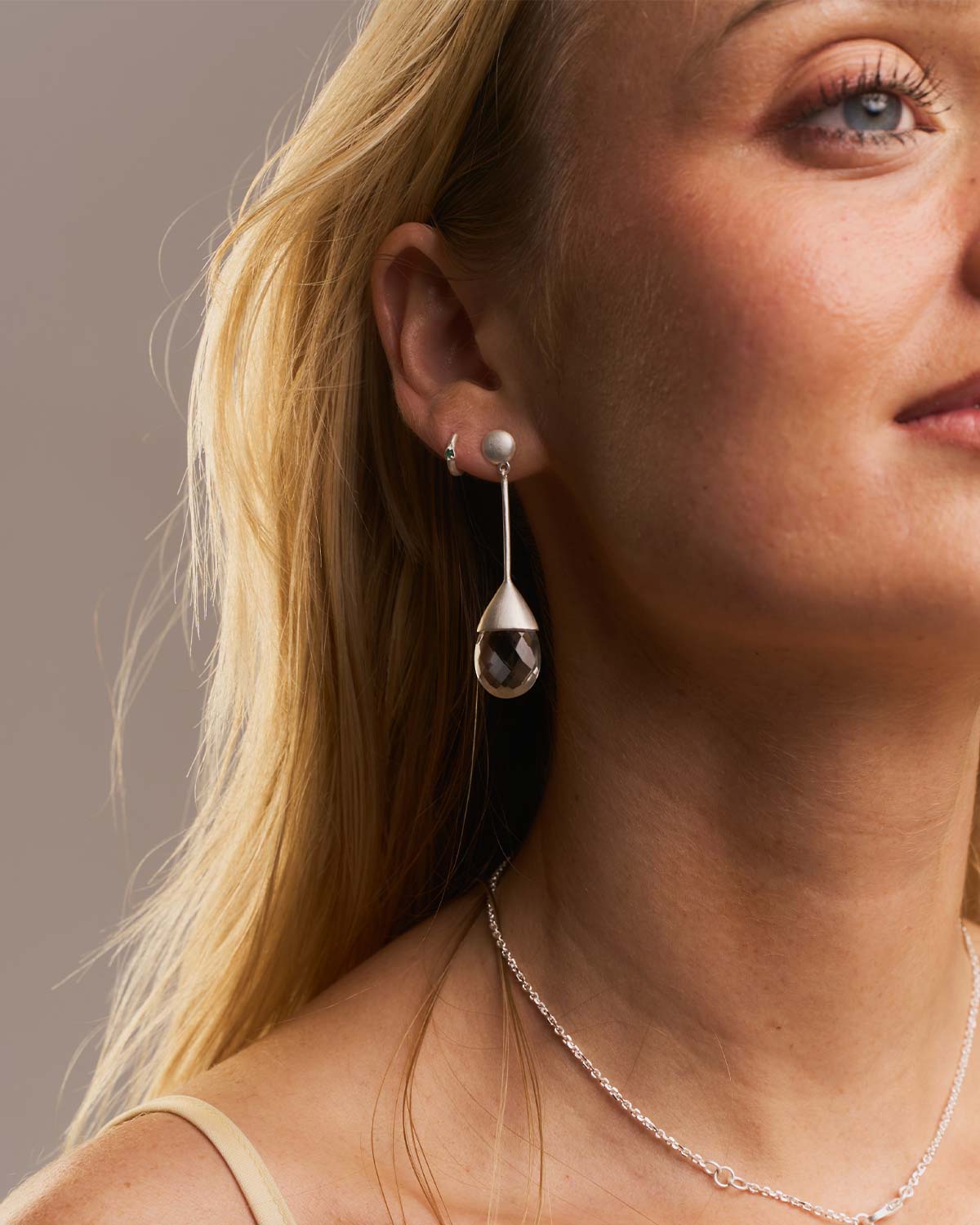 Model wearing neutral crystal drop earrings in a gold vermeil setting