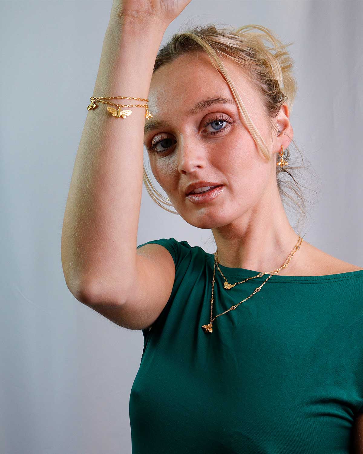 Model wearing gold butterfly necklace with blue topaz and pink tourmaline, adjustable chain