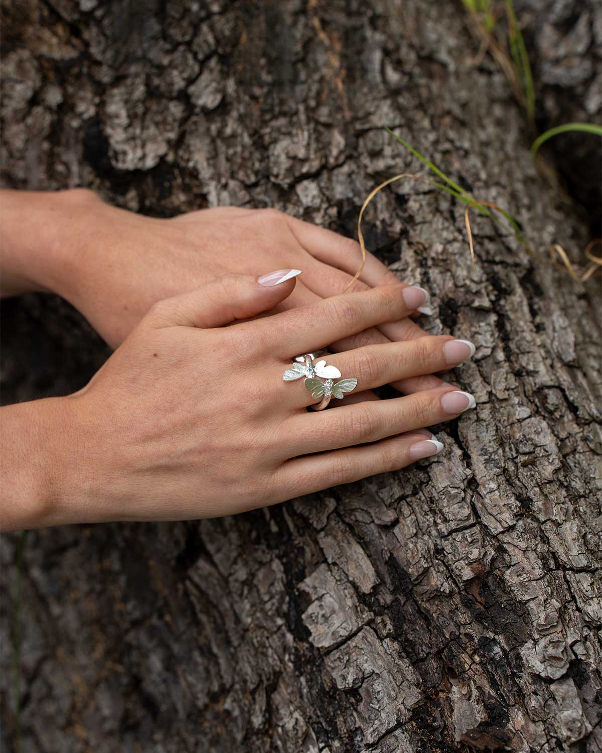Model wearing adjustable silver ring with Swiss Blue Topaz and butterfly motifs