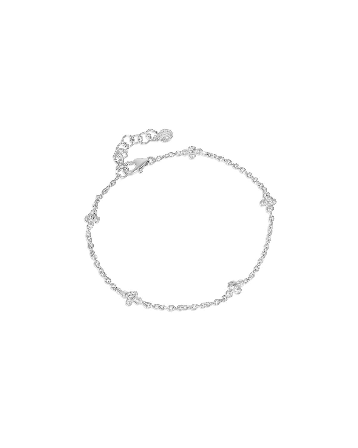 Silver bracelet styled with other bracelets featuring blue topaz gemstones and moissanite diamonds