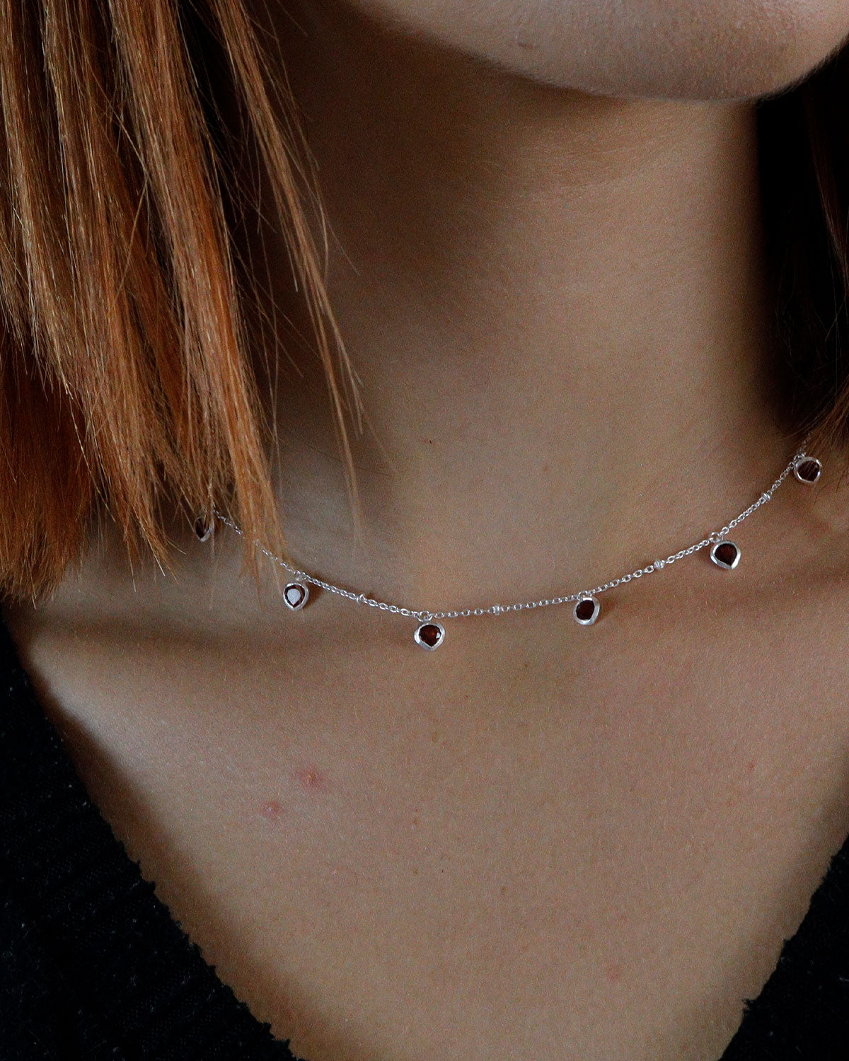 Model wearing a sterling silver heart necklace with a garnet gemstone pendant