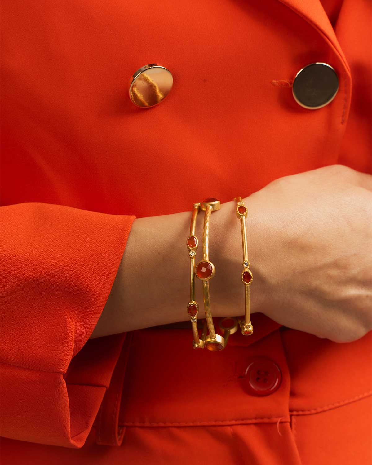 Close-up of a gold bangle with a natural carnelian gemstone and hammered texture