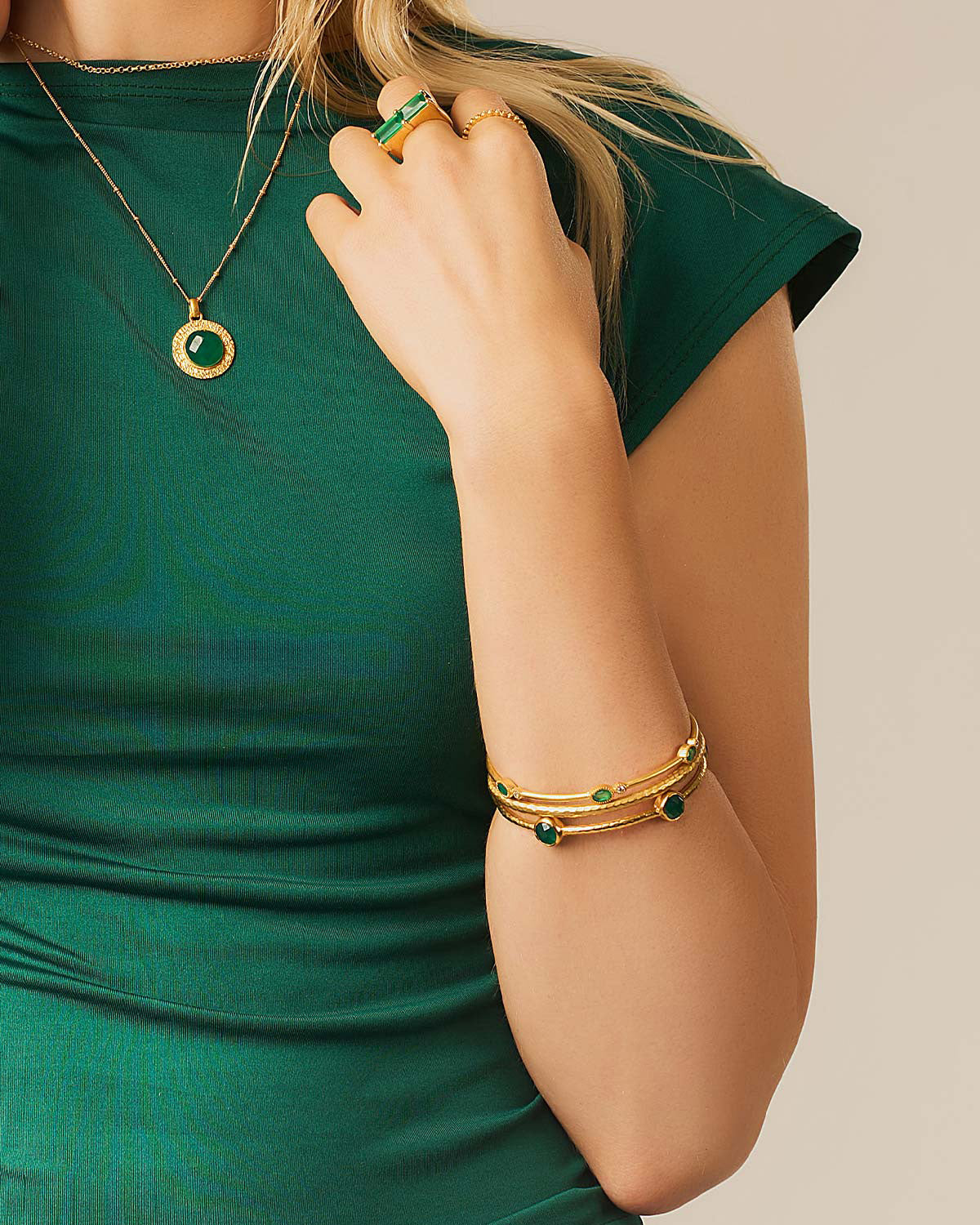 Detailed view of hammered texture and green onyx gemstones on gold bangle