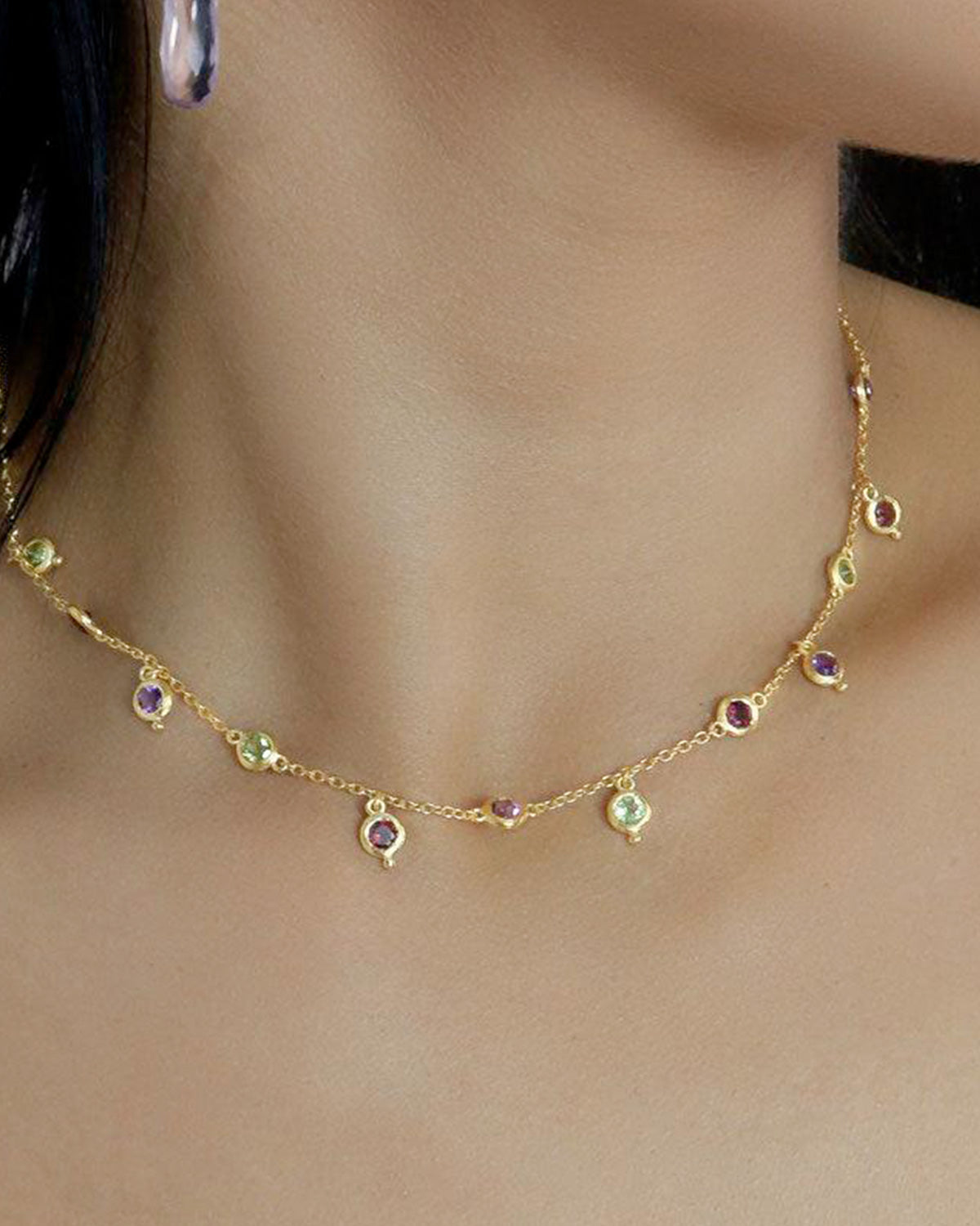 Model wearing gold necklace with rainbow moonstone and mixed gemstones