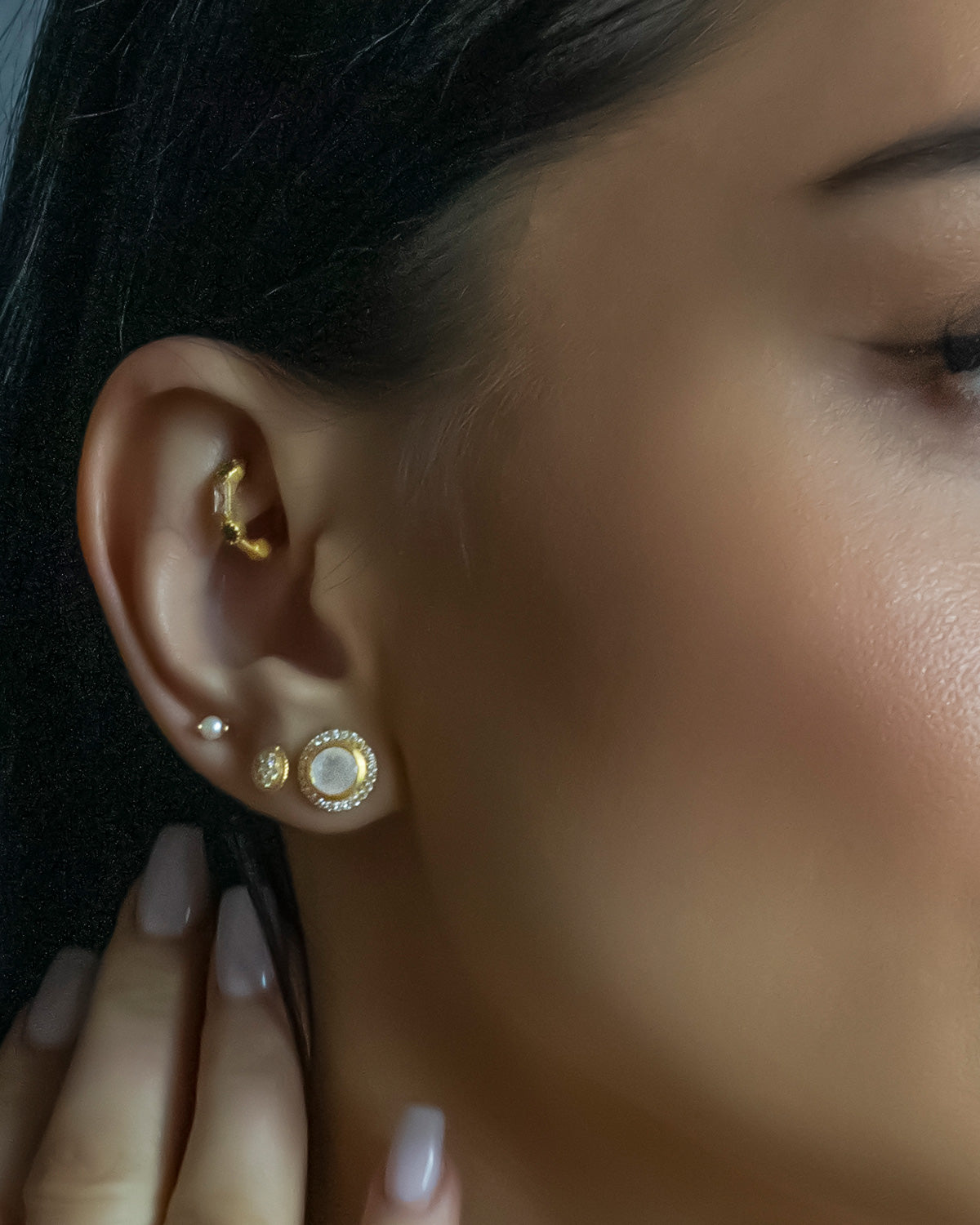 Model wearing gold stud earrings with moonstone and labradorite
