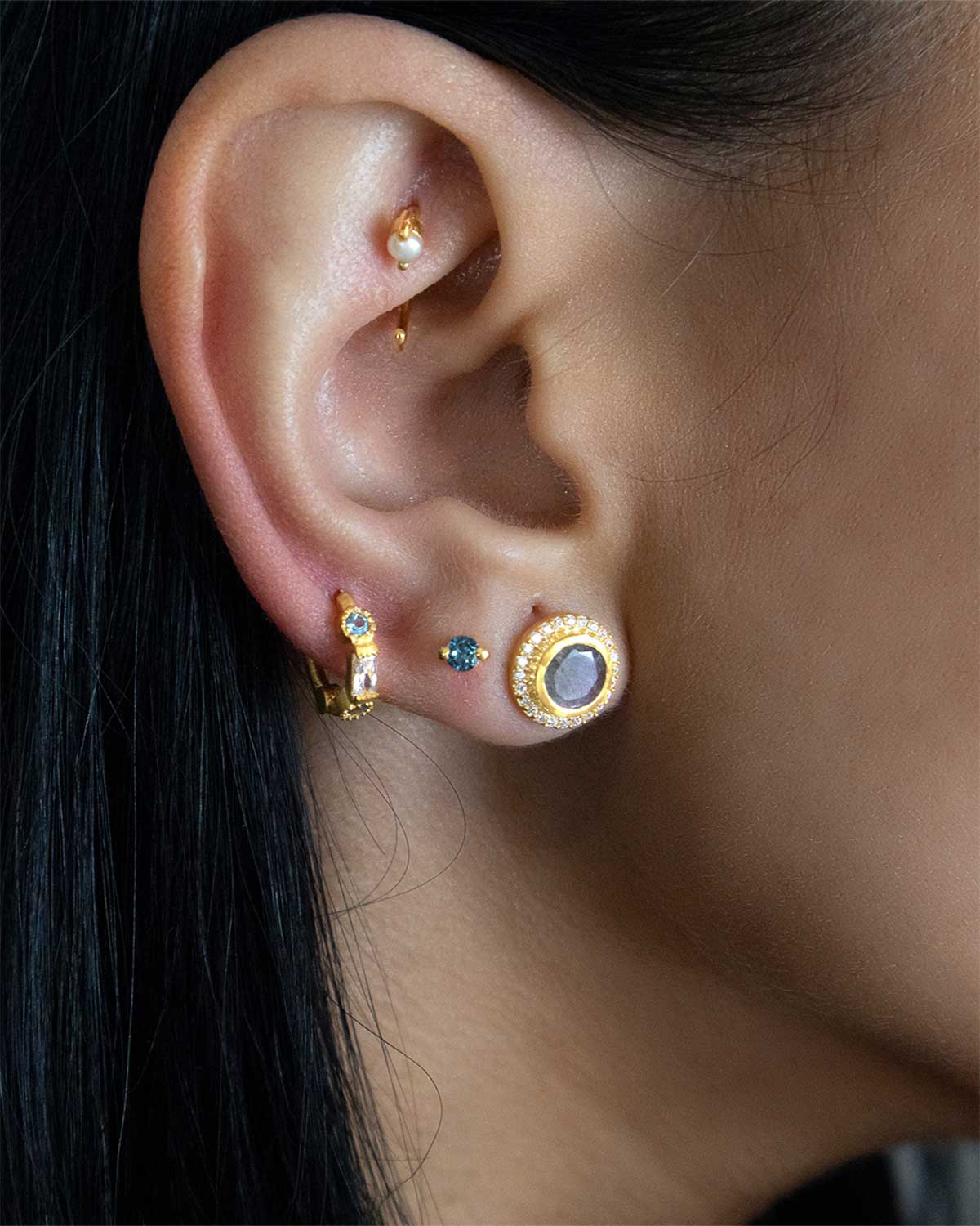 Model wearing silver stud earrings with moonstone and labradorite gemstones