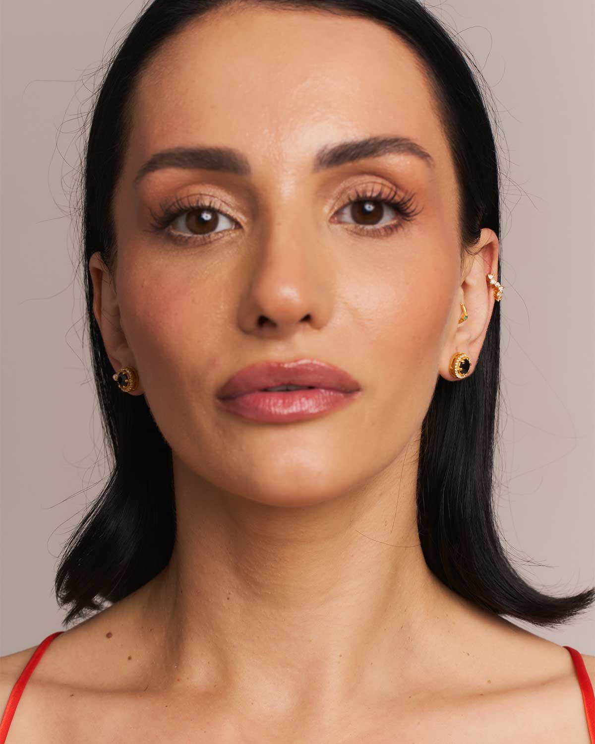 Model wearing gold stud earrings with black spinel and labradorite gemstones