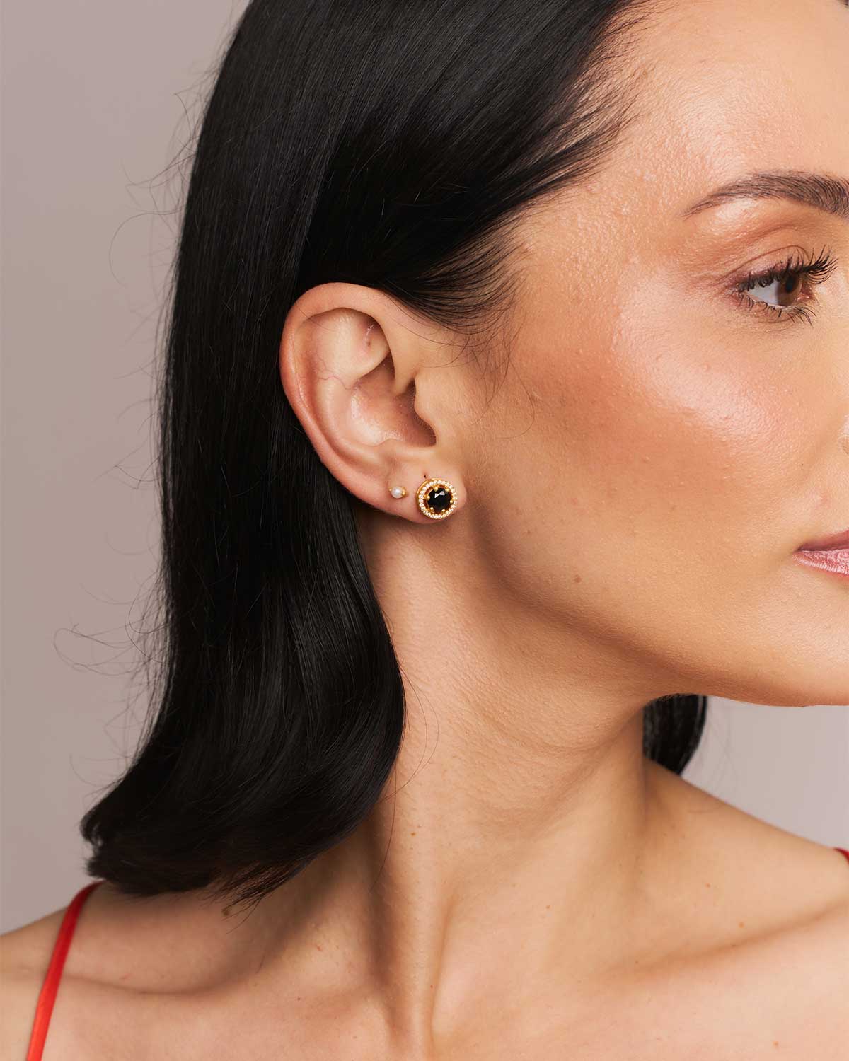 Side view of gold stud earrings with polished finish and natural gemstones