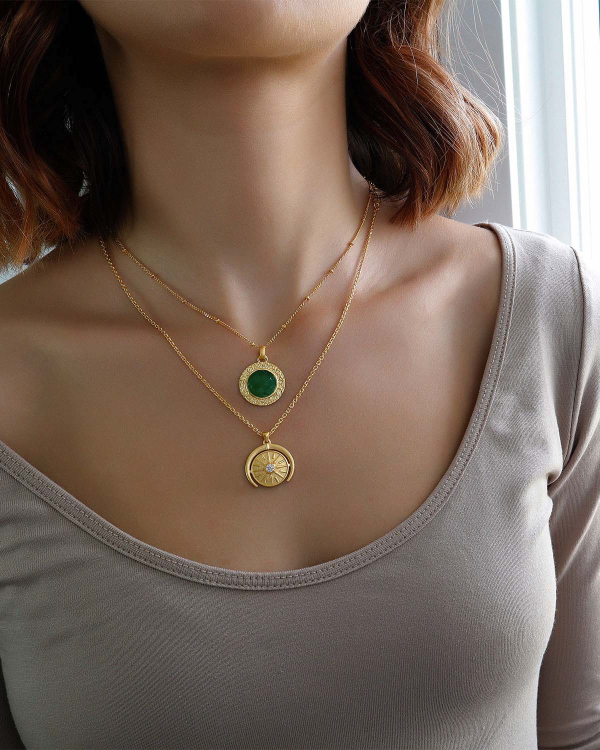 Close-up of circular gold pendant necklace with a single diamond