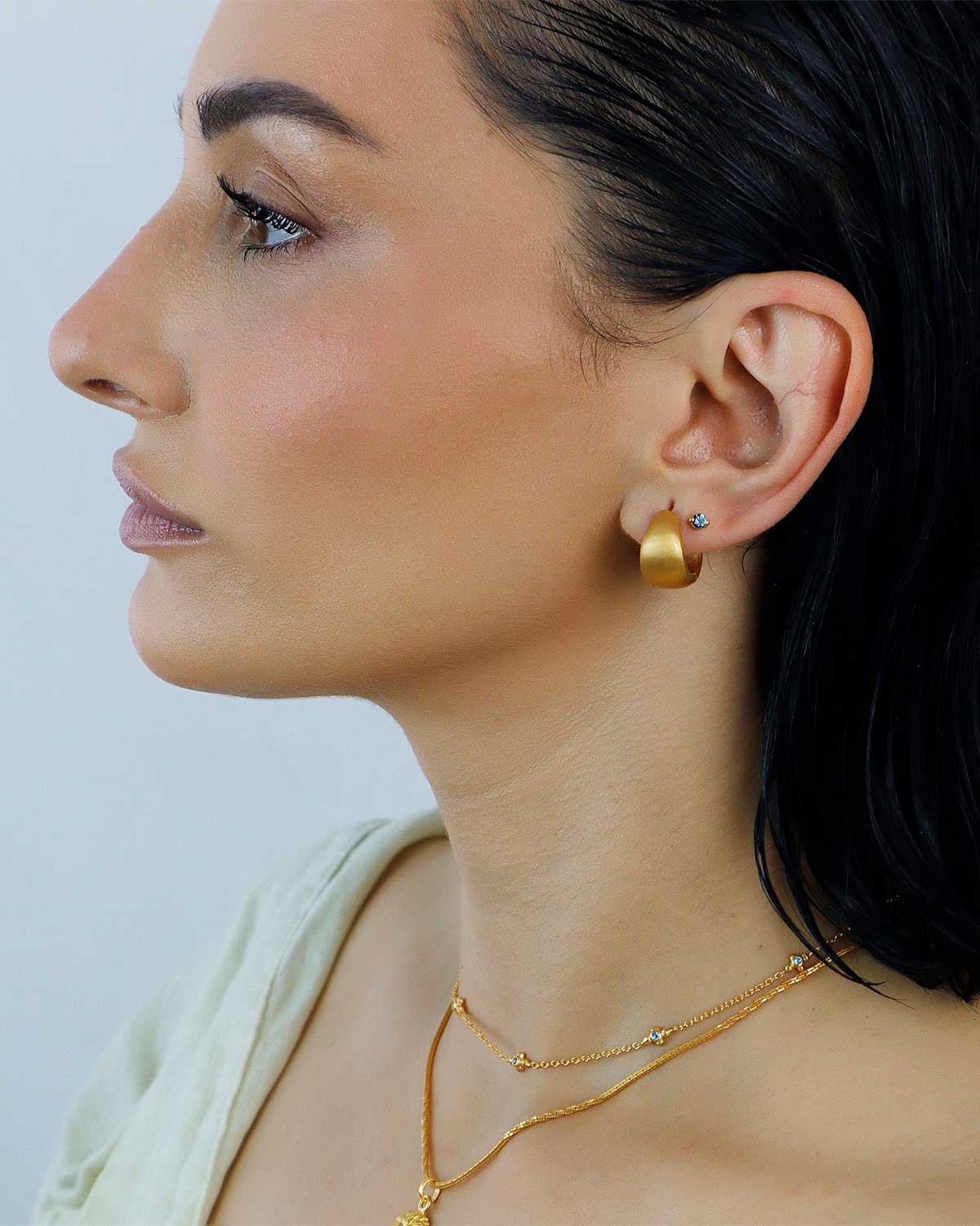 Close-up of mini chunky gold hoop earrings with a satin finish