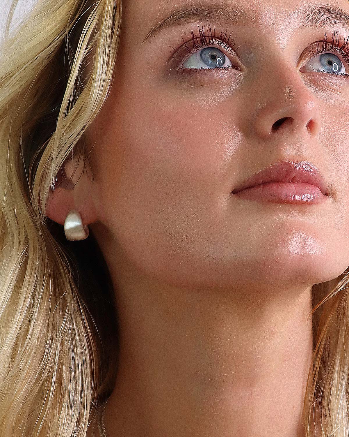 Close-up of silver mini hoop earrings with a silky satin finish