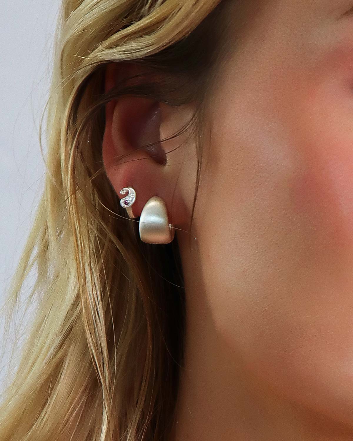 Side view of silver mini hoop earrings with a rounded chunky design