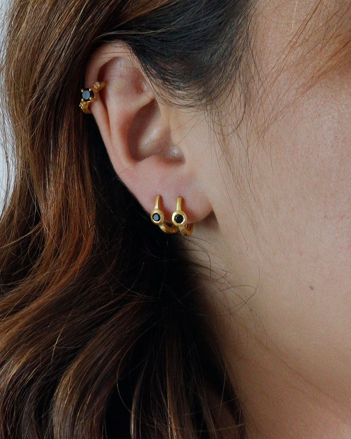 Gold mini hoop earrings styled with other hoops and gemstone studs
