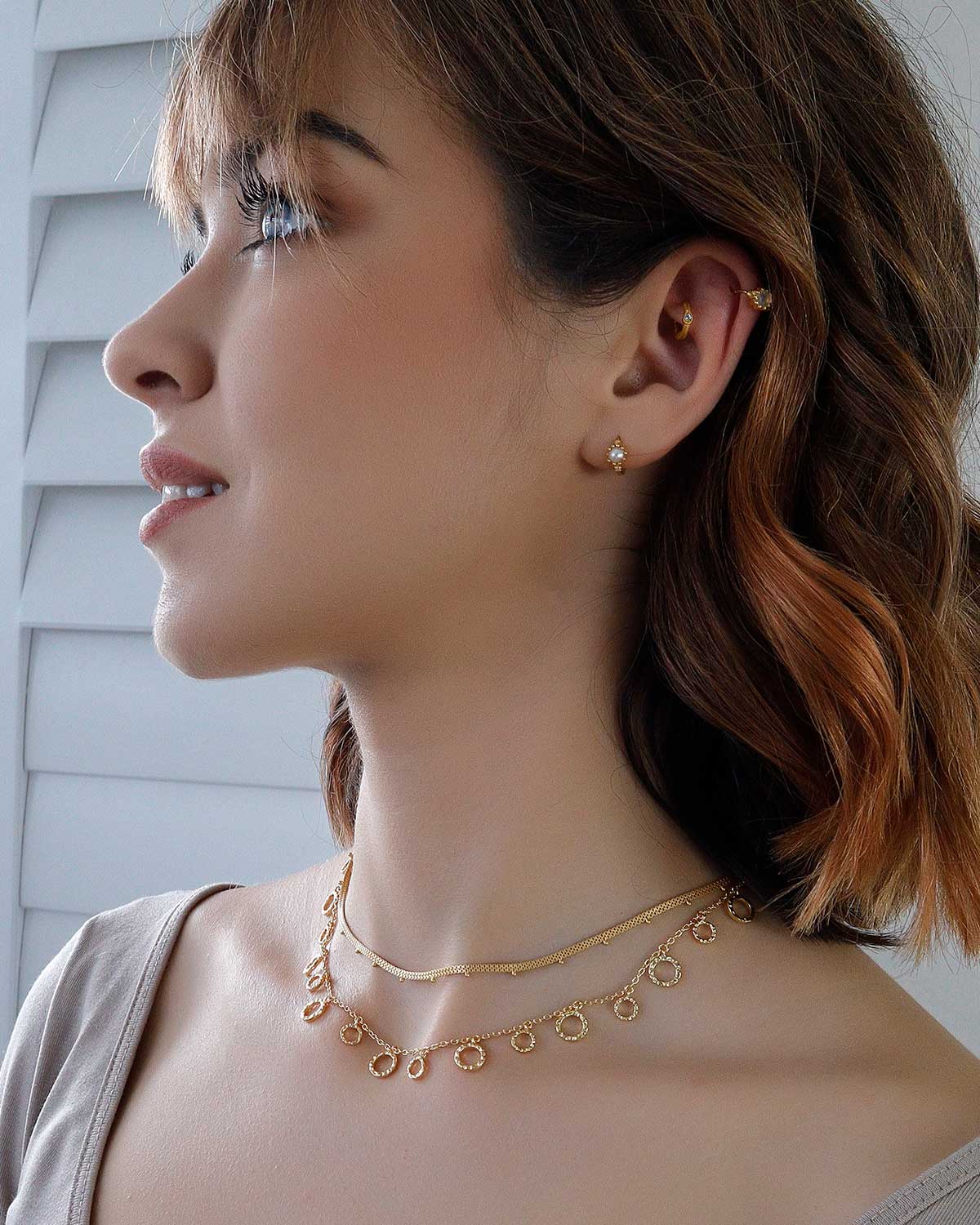 Model wearing gold huggie earrings with pink amethyst and labradorite stones