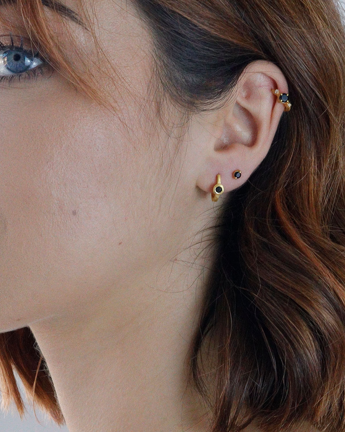 Close-up of gold mini hoops with black spinel gemstones