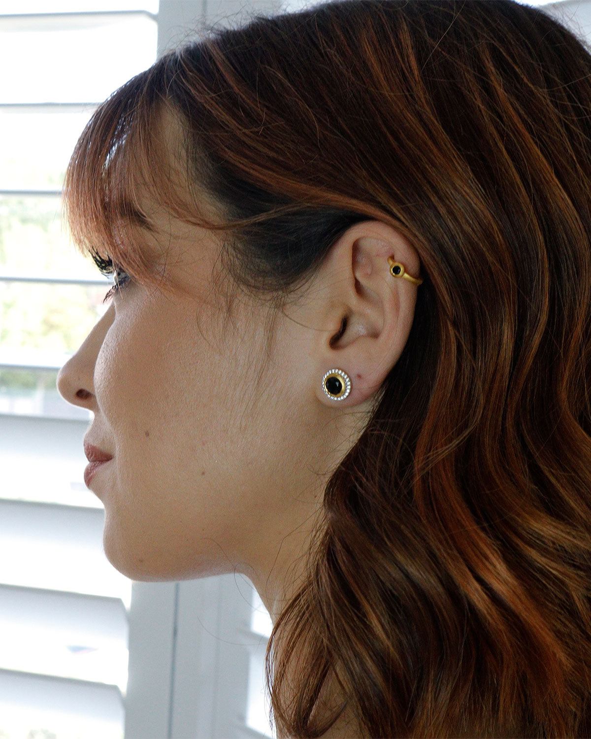 Gold mini hoop earrings with black spinel styled with other earrings