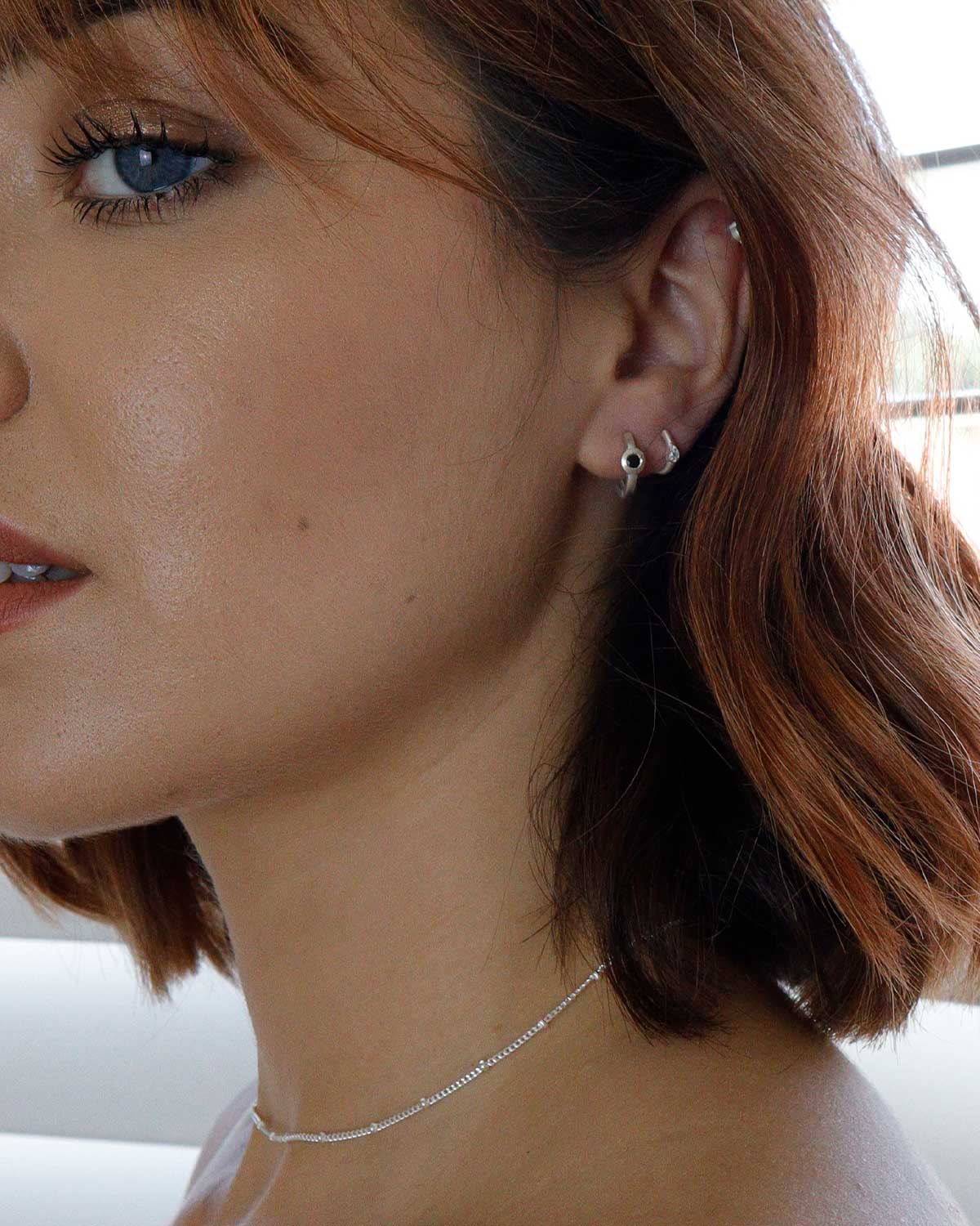 Side angle of silver mini hoops featuring black spinel gemstones