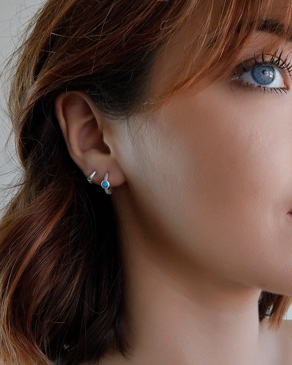 Close-up of silver mini hoops with hand-cut turquoise gemstones