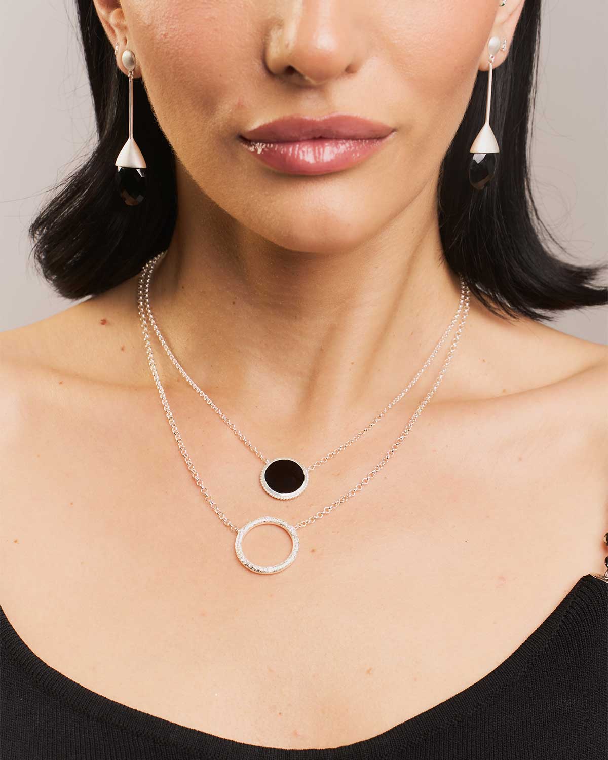 Front view of silver necklace featuring a diamond-studded circular pendant