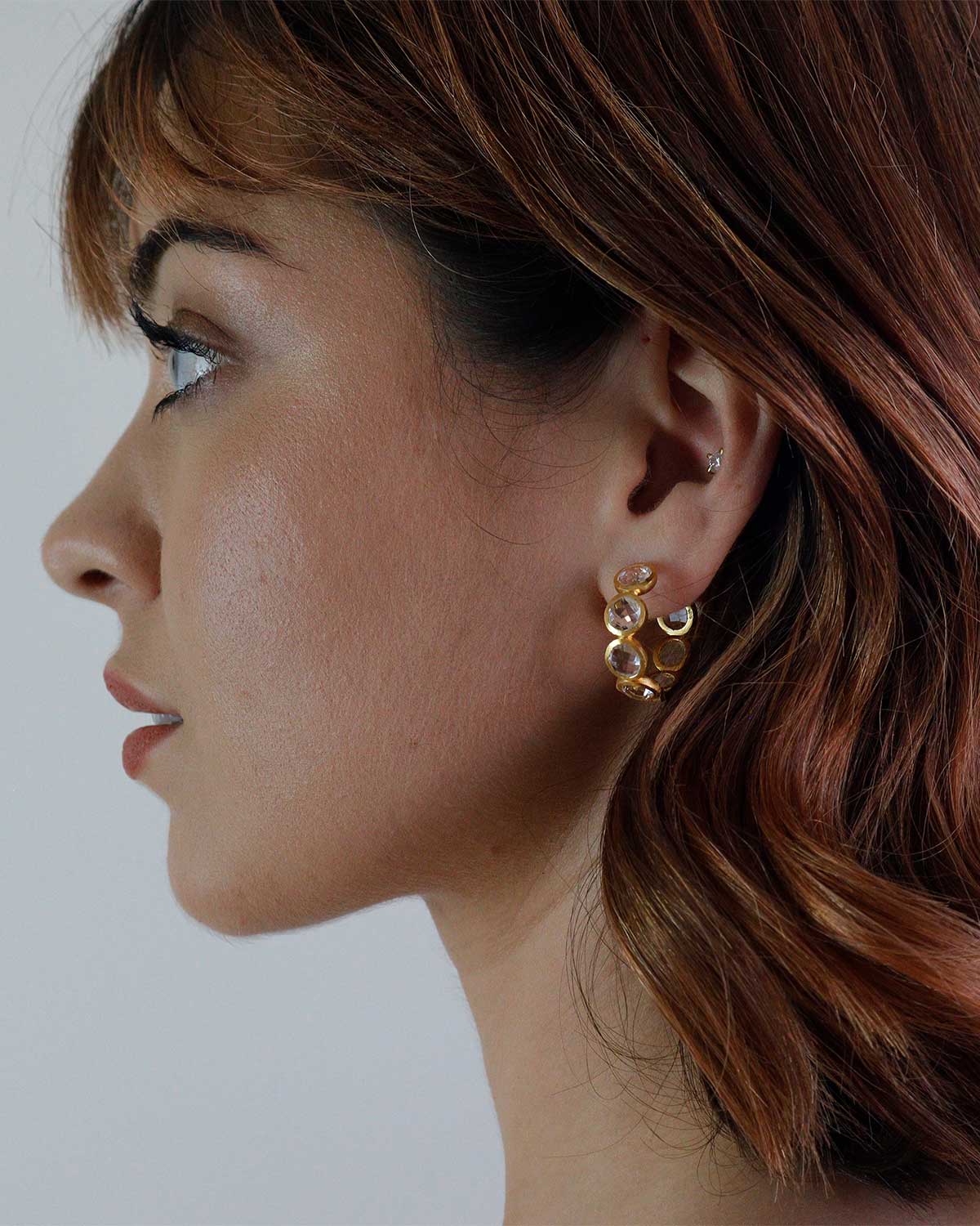 Side angle of gold hoop earrings with natural crystal gemstones