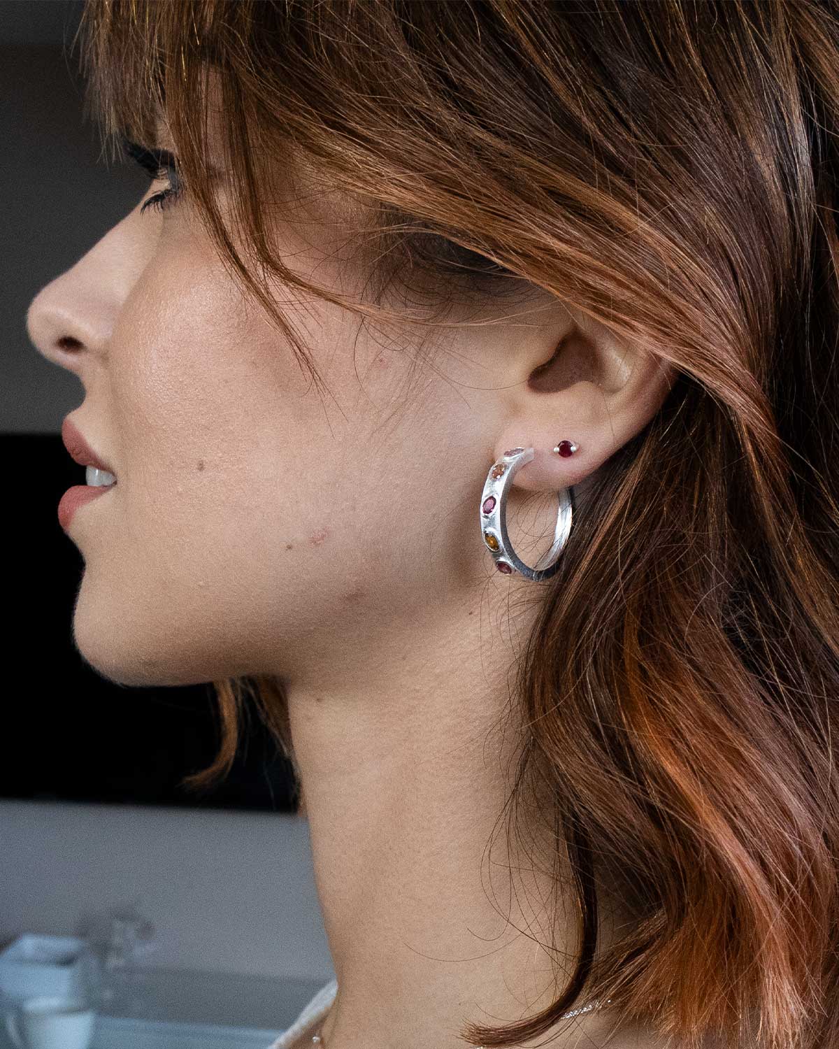 Close-up of silver hoops with mixed tourmaline gemstones in vibrant colours