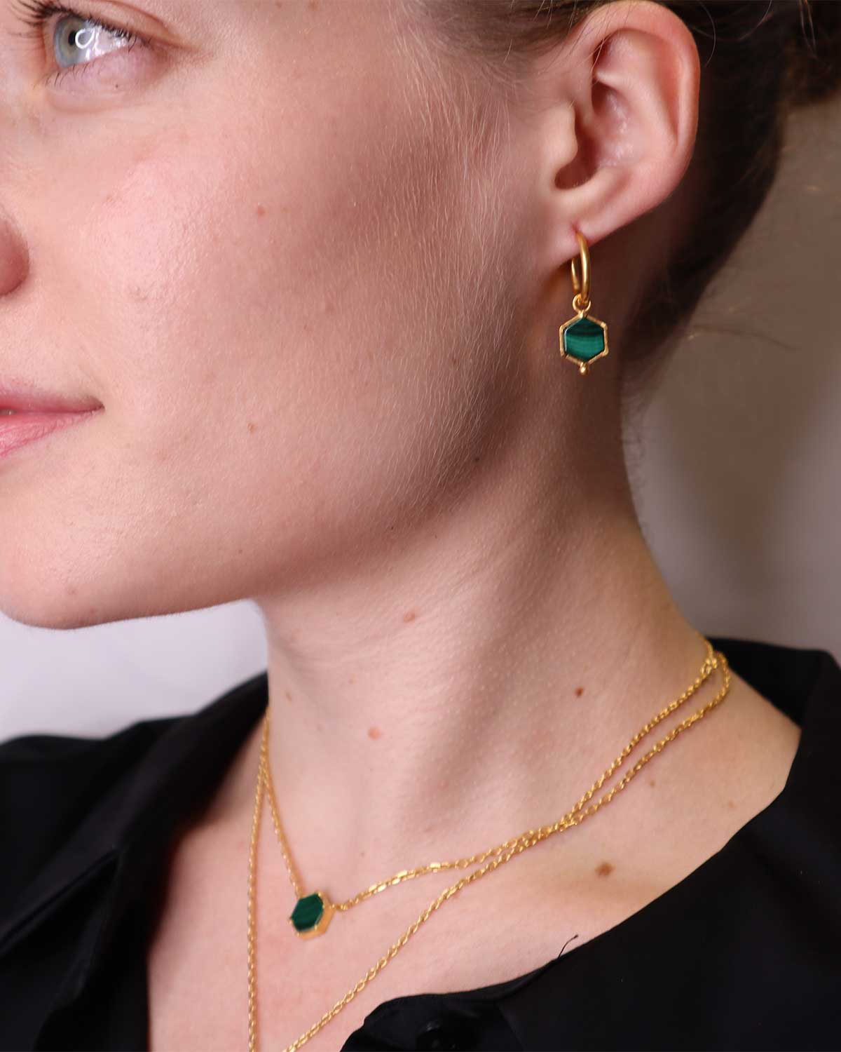 Model wearing a gold necklace with a natural malachite gemstone